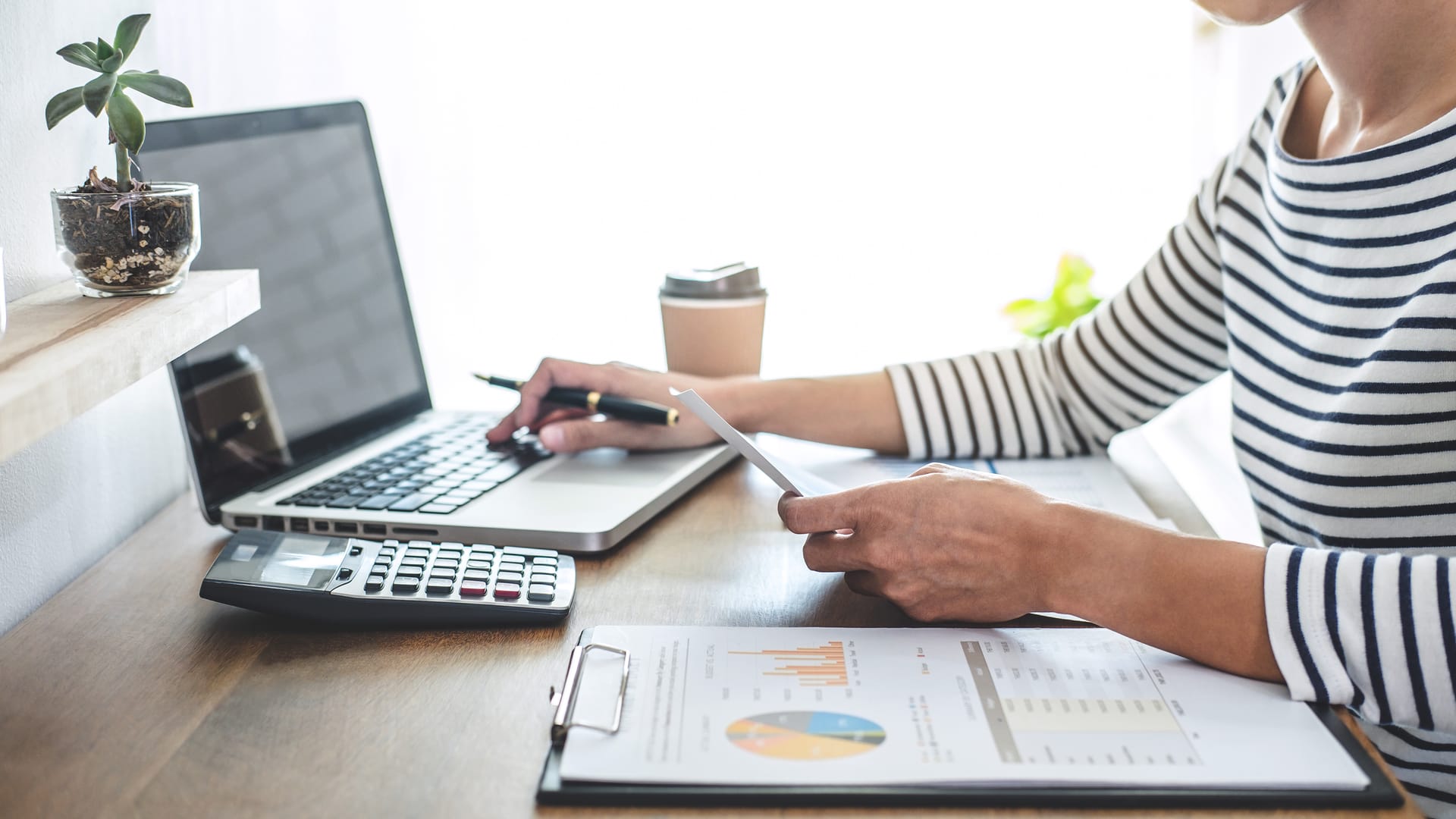 Accountant analyzing financial graphs with a calculator and laptop